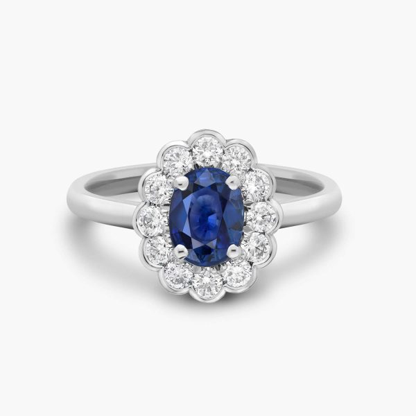 Platinum engagement ring featuring a oval-cut ceylon sapphire center stone surrounded by a halo of round brilliant-cut diamonds, elegantly set in a semi-bezel setting for a classic sophisicated look.