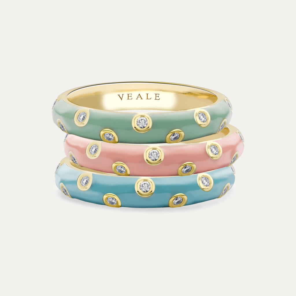 Three gold rings with bezel set diamonds zig zagging and enamel in powder blue, dusky pink and mint green.