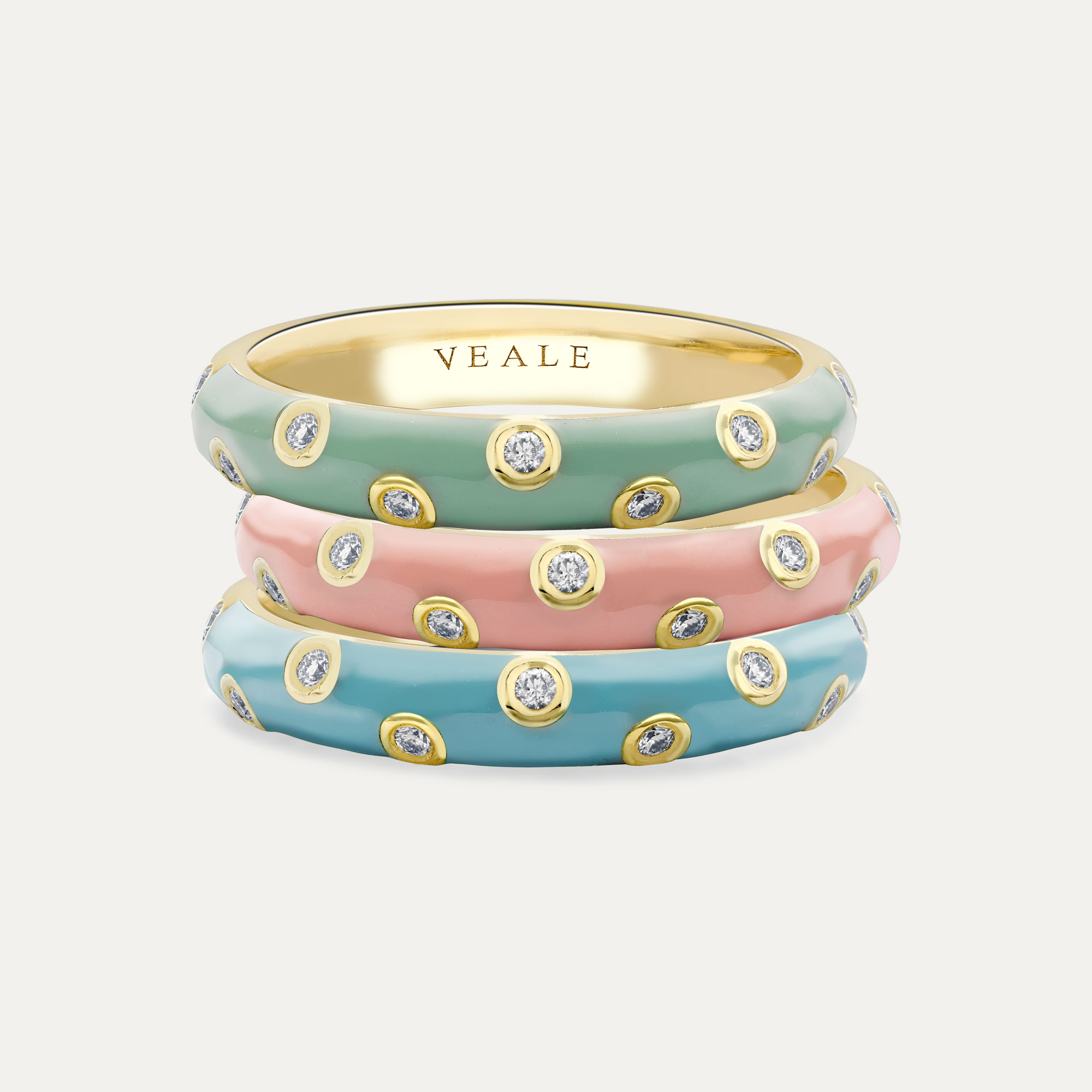 Three gold rings with bezel set diamonds zig zagging and enamel in powder blue, dusky pink and mint green.